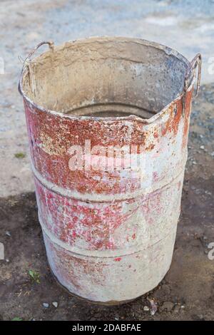 Auf der Straße steht ein altes rostiges Metallfass, das mit bunten Flecken bedeckt ist. Alles für Reparatur, Bau Stockfoto