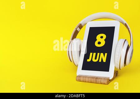 Juni. Tag 8 des Monats, Kalenderdatum. Elegante Kopfhörer und modernes Tablet auf gelbem Hintergrund. Leerzeichen für Text. Bildung, Technologie, Lifestyle. Stockfoto