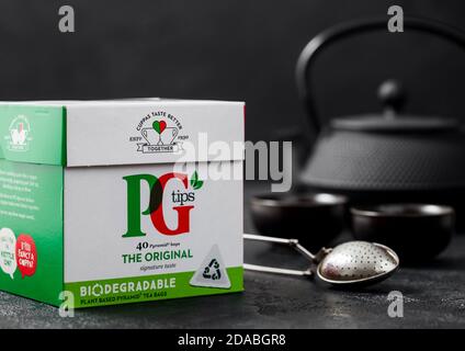 LONDON, UK - 21. OKTOBER 2020: Pack von PG Tipps schwarzen Tee mit Eisen Teekanne und vintage Sieb Infuser auf schwarzem Hintergrund. Stockfoto