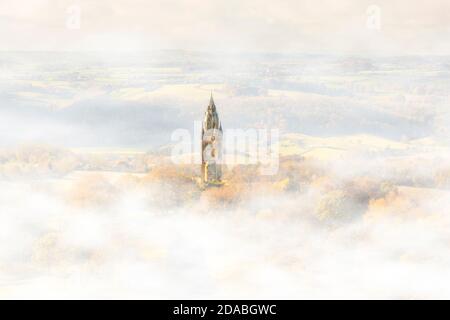 Abberley Uhrturm (Mini Big Ben) platzt durch den Nebel, während die aufgehende Herbstsonne durch das Tal strömt und den Uhrenturm erleuchtet. Stockfoto