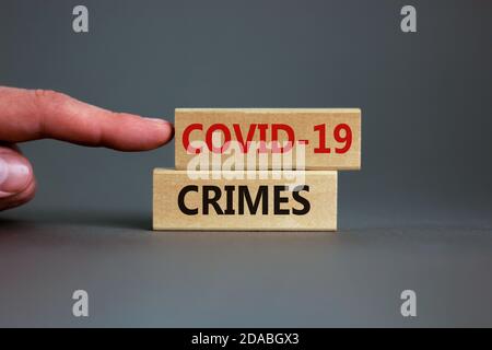 Konzeptwörter 'COVID-19 Crimes' auf Blöcken auf einem schönen grauen Hintergrund, männliche Hand. Speicherplatz kopieren. Business und covid-19 Pandemiekonzept. Stockfoto