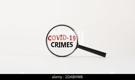 Lupe mit den Worten 'covid-19 Crimes' auf schönem weißen Hintergrund. Geschäftskonzept, Kopierbereich. Stockfoto