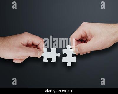 Hände von zwei Personen, die zwei Puzzleteile zusammenfügen, Lösungen finden und Teamwork-Konzept Stockfoto
