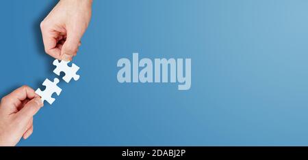 Hände von zwei Personen, die zwei Puzzleteile zusammenfügen, Lösungen finden und Teamwork-Konzept Stockfoto