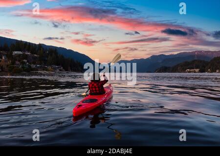 Abenteuerliches Mädchen paddelt auf einem hellen roten Kajak Stockfoto