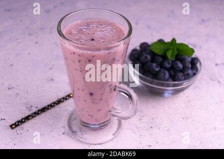 Bio-Heidelbeer-Smoothie in einem hohen Glas und frische Heidelbeeren auf weißem Hintergrund. Stockfoto