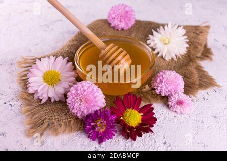 Frischer Blumenhonig und Blumen auf weißem Hintergrund. Stockfoto