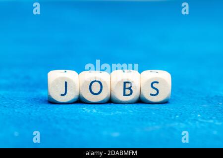 Jobs Wort mit Holzbuchstabenwürfel auf einem Klassiker gemacht Blauer Hintergrund Stockfoto