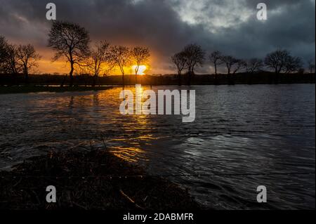 Caheragh, West Cork, Irland. November 2020. Die Sonne geht über überfluteten Feldern in Caheragh, nahe Skibbereen, nach einem Tag sintflutartigen Regens unter. Die Überschwemmung kommt inmitten einer Met Éireann gelben Wetterwarnung für die Grafschaft Cork, die bis heute Abend um 18 Uhr stattfindet. Quelle: AG News/Alamy Live News Stockfoto