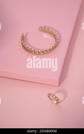 Kette Form goldenes Armband und Ring auf rosa Hintergrund Mit Kopierbereich Stockfoto