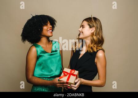 Eine junge schwarze Frau schenkt ihrer kaukasischen Freundin ein Urlaubsgeschenk. Konzept von Neujahr, Geburtstag oder Geburtstag. Stockfoto