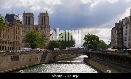 Paris, France - 09/07/2019: Reflexionen der hellen Herbstsonne im Wasser des seine Flusses mit der berühmten Kathedrale Notre-Dame de Paris und der Menge der Touristen. Stockfoto