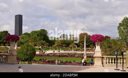 Paris, Frankreich - 09/07/2019: Menschen genießen die Herbstsonne im beliebten Park Jardin du Luxembourg mit einem Teich umgeben von Palmen. Stockfoto