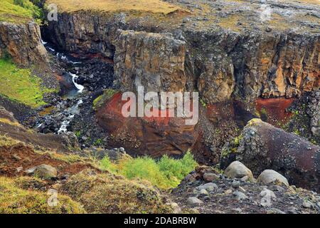 Hengifoss Canyon mit dem Hengifoss Wasserfall ist der dritthöchste Wasserfall Islands von basaltischen Schichten mit roten Lehmschichten umgeben Stockfoto