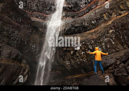 Hengifoss Canyon mit dem Hengifoss Wasserfall ist der dritthöchste Wasserfall Islands von basaltischen Schichten mit roten Lehmschichten umgeben Stockfoto