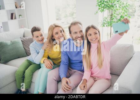 Foto von positiven Familie Menschen Mama Papa sitzen Couch Kind Mädchen machen Selfie auf dem Smartphone im Haus drinnen Stockfoto