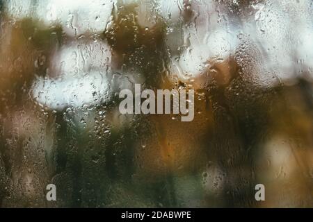 Verschwommenes Spiegelbild der Straße in einem Nebelfenster, Wassertropfen nach Regen fließen ins Glas. Wassertropfen auf dem Fenster. Konzept für Regentage. Stockfoto