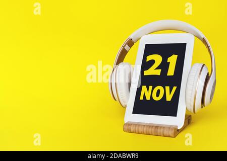 November. Tag 21 des Monats, Kalenderdatum. Elegante Kopfhörer und modernes Tablet auf gelbem Hintergrund. Leerzeichen für Text. Bildung, Technologie, Leben Stockfoto