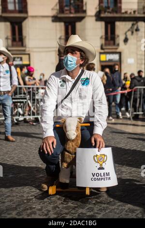 11. November 2020: Der Protestant mit Schutzmaske sitzt auf einem Spielzeug-Pferd und trägt ein Banner mit der Aufschrift: Wir wollen mitmachen. Katalanische Sportverbände und -Organisationen haben in Barcelona demonstriert, um die Wiedereröffnung von Fitnessstudios und Sportanlagen in Katalonien zu fordern.Quelle: Thiago PrudÃªNcio/DAX/ZUMA Wire/Alamy Live News Stockfoto
