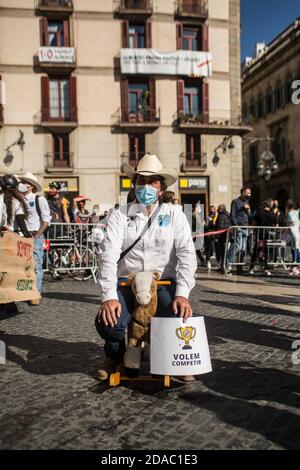 11. November 2020: Der Protestant mit Schutzmaske sitzt auf einem Spielzeug-Pferd und trägt ein Banner mit der Aufschrift: Wir wollen mitmachen. Katalanische Sportverbände und -Organisationen haben in Barcelona demonstriert, um die Wiedereröffnung von Fitnessstudios und Sportanlagen in Katalonien zu fordern.Quelle: Thiago PrudÃªNcio/DAX/ZUMA Wire/Alamy Live News Stockfoto