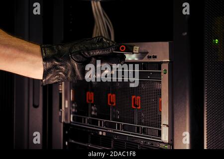 Hand mit einem Flash-Laufwerk von einem Hacking-Gerät am Server. Konzept von Datenintegritätsproblemen und Hackerangriffen Stockfoto