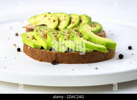 Avocado-Sandwiches auf weißem Teller auf hellem Hintergrund. Stockfoto