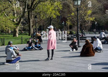 Eine Gruppe von Freunden in NYC Park Soziale Distanzierung in Ein Kreis zusammen während Covid-19 Lockdown Stockfoto