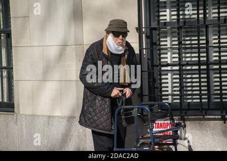 Älterer Mann, der in Manhattan herumläuft und Zigarre rauchen, während er eine Maske trägt Während der Covid-19-Pandemie Stockfoto