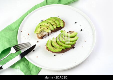 Zwei frische Avocado-Sandwiches auf einem weißen Teller. Stockfoto