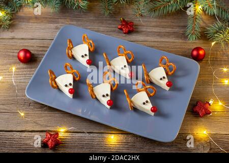 Lustige weihnachts-Snack in Form von Hirschen für Kinder Party. Konzept Neujahrskost aus Käse und Brezeln auf Holzhintergrund Stockfoto