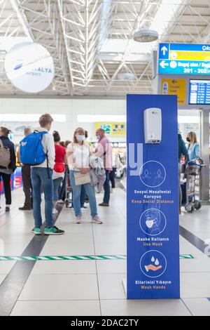 Antalya, Türkei-circa Okt, 2020: Antibakterieller Dispenser befindet sich im terminal des intarnationalen Flughafens. Ein Hinweisbrett mit Regeln fordert die Leute auf, ein soziales di zu halten Stockfoto