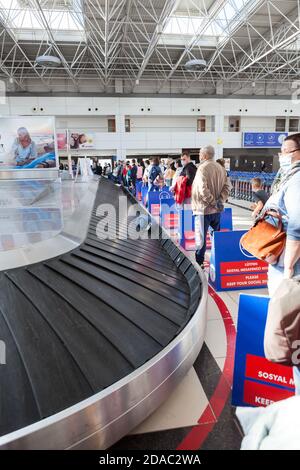 Antalya, Türkei-circa Okt, 2020: Passagiere warten im Flughafenterminal auf Gepäck, ohne eine soziale Distanz zu halten. Hinweisbretter fragen sie t Stockfoto