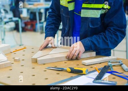 Professioneller Zimmermann, der mit hölzernen Details auf der rauen Werkbank in der Werkstatt arbeitet. Design, Zimmerei, Arbeit, Arbeitsplatz, Handwerk und Handarbeit Stockfoto