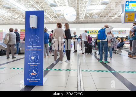 Antalya, Türkei-circa Okt, 2020: Spender mit antibakteriellem Gel ist im Antalya International Airport. Schilder mit Benachrichtigung über das Halten von Socia Stockfoto