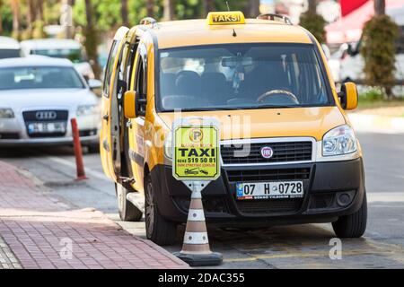 Alanya, Türkei-ca. Okt, 2020: Gelbe Kabine steht auf dem speziellen Parkplatz für Taxiwagen. Transporter mit geöffneten Türen wartet auf Passagiere. Taxi Stockfoto