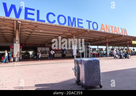 Antalya, Türkei-circa Okt, 2020: Zwei Gepäckwagen stehen gegen das Schild des Antalya International Airport. Inschrift das Willkommen in Antalya ist in einem Stockfoto