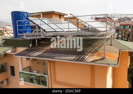 Solar-Glas-Wasser-Panel-Array auf einem Dach für die Heizung montiert. Riesiger Tank für heißes Wasser. Heizung mit grüner Energie für Hotelbedürfnisse Stockfoto