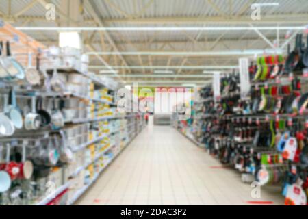 Verschwommener Supermarkt-Hintergrund. Verkauf von Haushaltswaren in einem Supermarkt. Küchenutensilien in den Regalen. Stockfoto