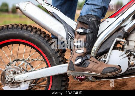 Nahaufnahme des Motocross-Kofferraums des Fahrers, der auf einem Dreck des Motorrades steht. Sicherheitsbekleidung für das Reiten Stockfoto