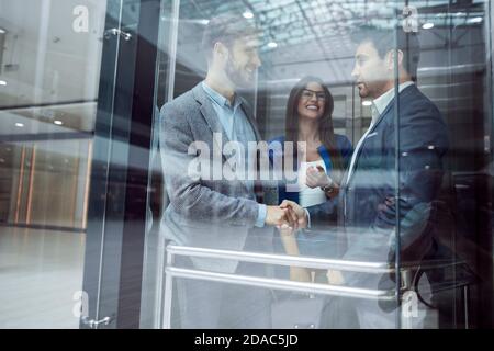 Kolleginnen und Kollegen die Hände schütteln im Elevato Stockfoto