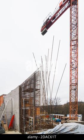 Bau von Stahlbeton Stützwand mit Stützpfeiler. Turmdrehkran. Stahlstäbe aus Stahlbeton im Gitter. Hervorstehende rostige Drähte. Stockfoto