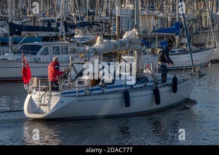 Ein Segler auf einer großen Yacht, der in den Yachthafen von lymington Harbour, solent, hampshire, großbritannien eindringt Stockfoto