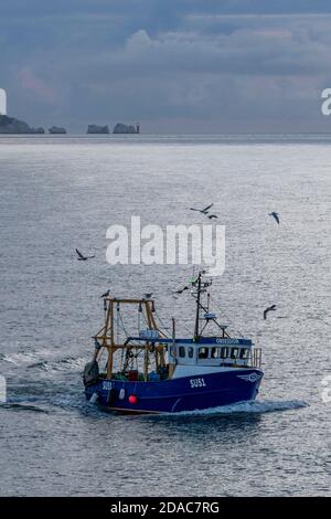 Ein kleiner Küstenfischtrawler, der nach Hause zurückkehrt, vorbei am Leuchtturm der Nadeln auf der Insel wight, großbritannien Stockfoto