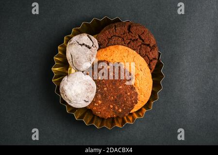 Teller mit süßem Gebäck auf schwarzem Hintergrund. Nahaufnahme von Cookies verschiedener Formen und Typen. Köstliches Dessert für den Urlaub. Hausmannskost Stockfoto