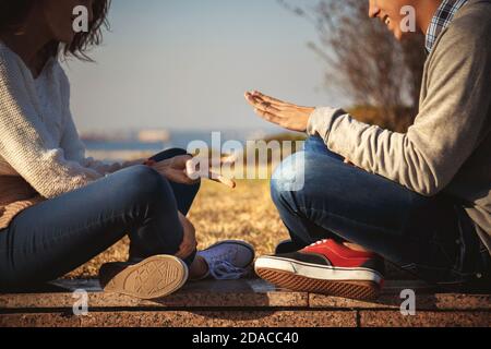Nahaufnahme von jungen paar Teens spielen Stein Papier Schere Spiel zusammen im Freien sitzen. Stockfoto