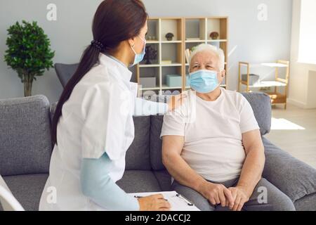 Freundlicher, unterstützender Arzt, der während einer Coronavirus-Pandemie ältere männliche Patienten besucht. Stockfoto