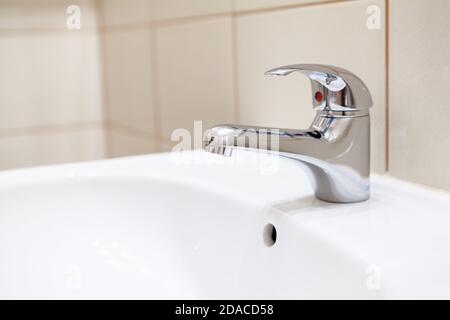 Edelstahlwasserhahn im weißen Waschbecken im Badezimmer Stockfoto