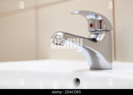 Edelstahl Wasserhahn, verchromte Metall Wasserhahn für das Badezimmer in weißem Waschbecken Stockfoto