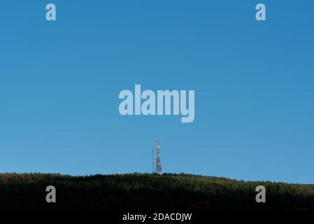 Ein Telekommunikationsturm auf dem Waldhügel mit klaren Blauer Himmel viel Platz für Werbetext sauber Scharfe Farben und Fokus Stockfoto