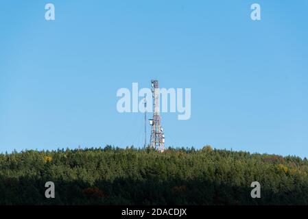 Ein Telekommunikationsturm auf dem Waldhügel mit klaren Blauer Himmel viel Platz für Werbetext sauber Scharfe Farben und Fokus Stockfoto